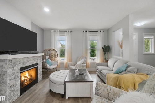 Living area with a stone-clad fireplace, wood-finish flooring, recessed lighting, and multiple windows - 7603 Summerside Grande Boulevard Sw, Edmonton, AB - Indoor Photo Showing Living Room With Fireplace