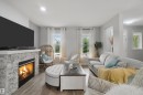 Living area with a stone-clad fireplace, wood-finish flooring, recessed lighting, and multiple windows - 7603 Summerside Grande Boulevard Sw, Edmonton, AB  - Indoor Photo Showing Living Room With Fireplace 