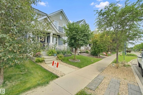 Two-story residence featuring light-colored siding, a covered porch with white railing, and dark shutters - 7603 Summerside Grande Boulevard Sw, Edmonton, AB - Outdoor