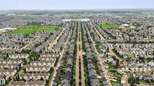 Expansive residential development featuring multiple housing styles, mature trees, green spaces, and a visible body of water - 7603 Summerside Grande Boulevard Sw, Edmonton, AB - Outdoor With View