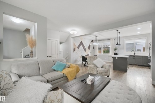 Open-concept living area with wood-finish flooring, a kitchen island, pendant lighting, and recessed lighting - 7603 Summerside Grande Boulevard Sw, Edmonton, AB - Indoor Photo Showing Living Room