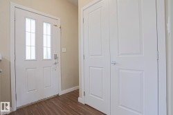 Entryway with a white paneled door featuring decorative glass inserts, a smart lock system, and wood-finish flooring - 