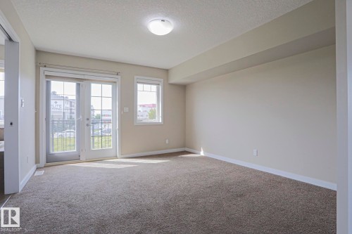 Wall-to-wall carpeting, white trim, and a flush mount ceiling light - #13 5873 Mullen Pl Nw, Edmonton, AB - Indoor Photo Showing Other Room