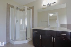Dark wood-finish vanity with a light-toned countertop, an integrated sink, and an expansive mirror - 