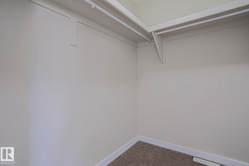 Built-in shelving with hanging rods and carpet flooring - #13 5873 Mullen Pl Nw, Edmonton, AB - Indoor Photo Showing Other Room