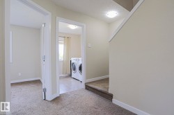 Bright upper-level hallway with neutral wall finishes, recessed ceiling lighting, and carpet flooring - 