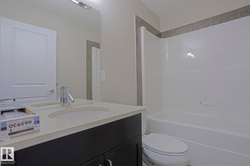 Vanity with light-toned countertop, undermount sink, and chrome faucet - #13 5873 Mullen Pl Nw, Edmonton, AB - Indoor Photo Showing Bathroom