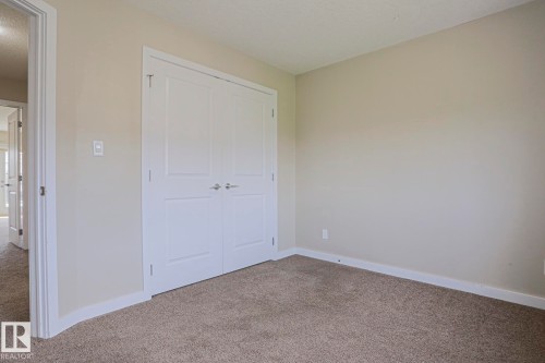 Neutral-toned walls, plush carpeting, and bright white trim - #13 5873 Mullen Pl Nw, Edmonton, AB - Indoor Photo Showing Other Room