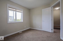 Neutral wall paint, plush carpet flooring, white trim, and a white interior door - 