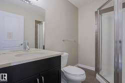 Dark wood-finish vanity with an integrated sink, polished chrome faucet, rectangular mirror, and an enclosed shower with glass panels - 