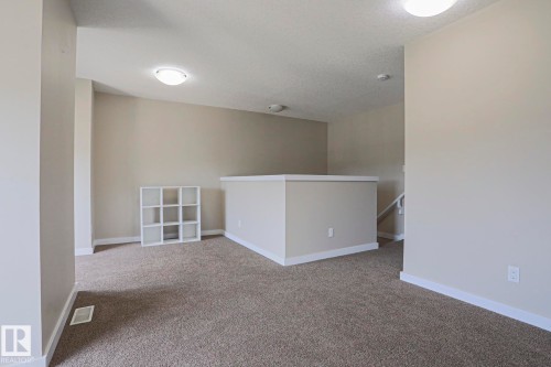 Carpeted landing area featuring a painted railing, neutral wall tones, and overhead lighting - #13 5873 Mullen Pl Nw, Edmonton, AB - Indoor Photo Showing Other Room