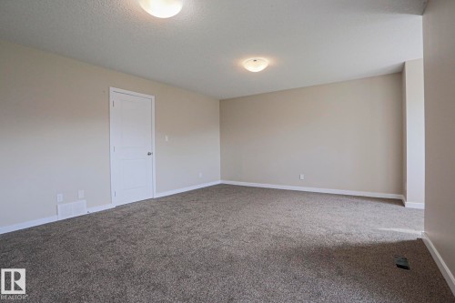 Spacious room with gray carpet flooring, neutral painted walls, and ceiling-mounted lighting fixtures - #13 5873 Mullen Pl Nw, Edmonton, AB - Indoor Photo Showing Other Room