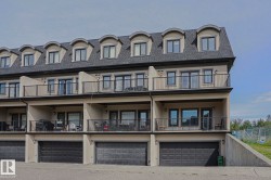 Multi-level townhome exterior featuring dormer windows, private balconies with black railings, ground-level patios, and individual garage access - 