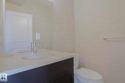 White solid surface countertop, integrated white sink, chrome faucet, dark wood-finish vanity, and wall-mounted mirror - 