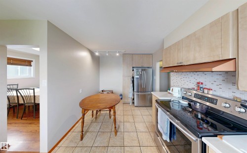 Kitchen featuring tile flooring, light-toned cabinetry, stainless steel appliances, and a tiled backsplash - 9531 74 Street Nw, Edmonton, AB - Indoor Photo Showing Kitchen