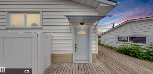 White horizontal siding with a window, outdoor light fixture, and a white entry door with an arched window - 9531 74 Street Nw, Edmonton, AB - Outdoor With Exterior