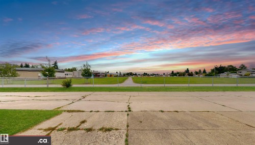 Expansive green space bordered by a chain-link fence, with buildings and mature trees in the background - 9531 74 Street Nw, Edmonton, AB - Outdoor With View