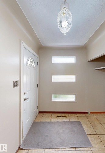 Tiled entry flooring with decorative pendant lighting and a white paneled door featuring a stained glass insert - 9531 74 Street Nw, Edmonton, AB - Indoor Photo Showing Other Room