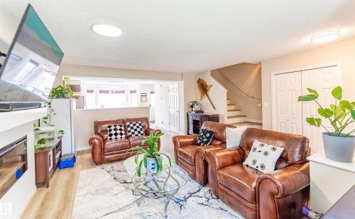 Living area featuring light wood-finish flooring, recessed lighting, a built-in fireplace, and a partial wall opening to an adjacent room - 8527 Ellis Link Nw, Edmonton, AB - Indoor Photo Showing Living Room With Fireplace
