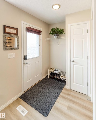 Foyer featuring wood-finish flooring, a white paneled entry door with frosted glass, and a flush-mount ceiling light - 8527 Ellis Link Nw, Edmonton, AB - Indoor Photo Showing Other Room