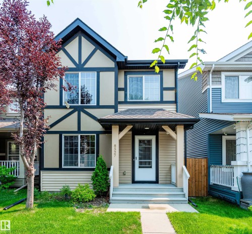 Tudor-inspired exterior featuring stucco and horizontal siding, with a welcoming covered front porch - 8527 Ellis Link Nw, Edmonton, AB - Outdoor With Facade