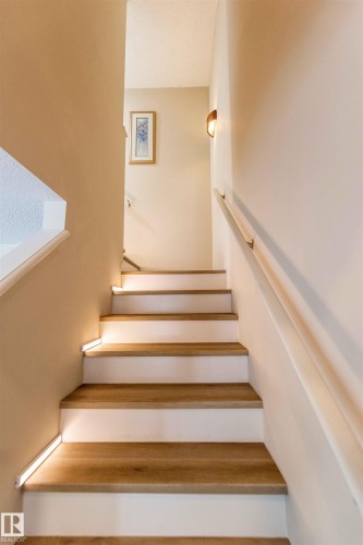 Staircase featuring wood-finish treads, white risers, and contemporary accent lighting - 8527 Ellis Link Nw, Edmonton, AB - Indoor Photo Showing Other Room