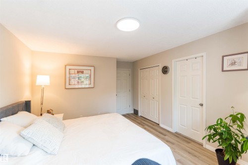 Bedroom featuring light neutral wall paint, wood-finish flooring, a flush-mount ceiling light, and white paneled doors - 8527 Ellis Link Nw, Edmonton, AB - Indoor Photo Showing Bedroom