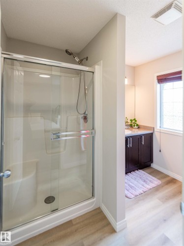 Shower enclosure with glass sliding doors, integrated bench seating, and a hand-held shower fixture - 8527 Ellis Link Nw, Edmonton, AB - Indoor Photo Showing Bathroom