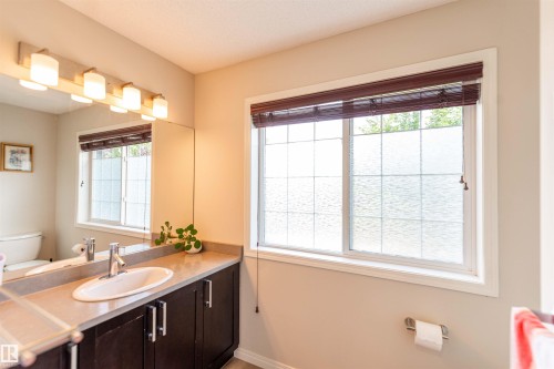 Bathroom vanity featuring dark wood-finish cabinetry, a light-toned countertop, and an oval undermount sink with a chrome faucet - 8527 Ellis Link Nw, Edmonton, AB - Indoor Photo Showing Bathroom