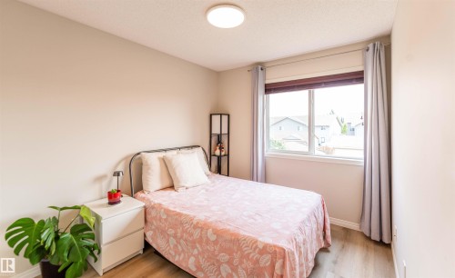 Light wood-finish flooring, a white window frame, and a flush-mount ceiling light fixture - 8527 Ellis Link Nw, Edmonton, AB - Indoor Photo Showing Bedroom