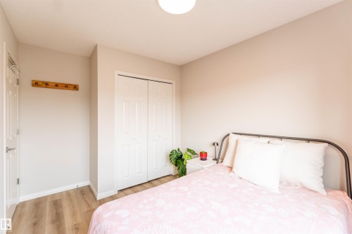 Neutral tone bedroom featuring wood-finish flooring, white baseboards, and a bi-fold closet with panel detailing - 8527 Ellis Link Nw, Edmonton, AB - Indoor Photo Showing Bedroom