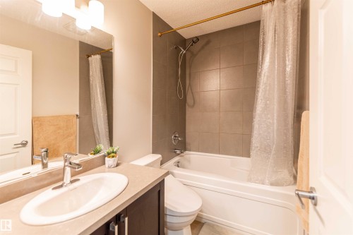 Bathroom featuring a built-in tub with a shower fixture and grey subway tile surround - 8527 Ellis Link Nw, Edmonton, AB - Indoor Photo Showing Bathroom