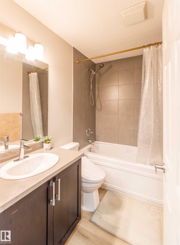 Bathroom featuring a dark wood-finish vanity, light-toned countertop, and a white integrated sink - 8527 Ellis Link Nw, Edmonton, AB - Indoor Photo Showing Bathroom