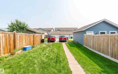 Expansive backyard featuring a concrete pathway, a detached blue-sided garage, and a wood privacy fence - 8527 Ellis Link Nw, Edmonton, AB - Outdoor
