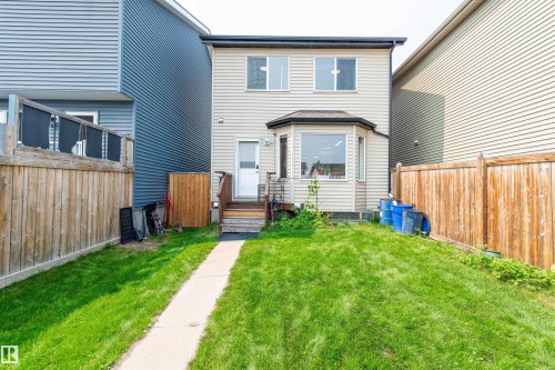Rear exterior featuring light-toned horizontal siding and a ground-level patio door - 8527 Ellis Link Nw, Edmonton, AB - Outdoor With Exterior