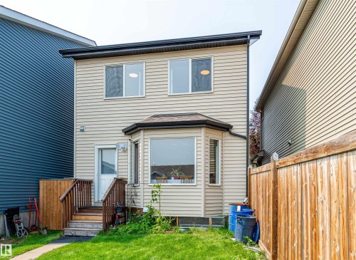Rear exterior featuring light-colored horizontal siding and a dark shingle roof - 8527 Ellis Link Nw, Edmonton, AB - Outdoor With Exterior