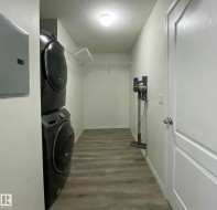 This laundry area features a stacked washer and dryer, a wire shelf, and light-toned flooring - 