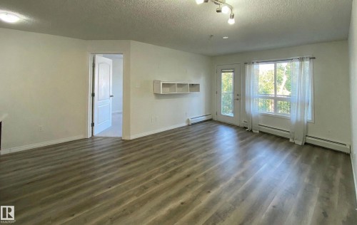 This living area features light-colored walls and wood-look flooring - #6125 7331 South Terwillegar Dr Nw, Edmonton, AB - Indoor With Fireplace