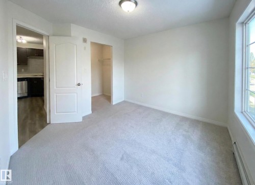This room features light-colored carpeting, a window providing natural light, and a closet with shelving - #6125 7331 South Terwillegar Dr Nw, Edmonton, AB - Indoor Photo Showing Other Room