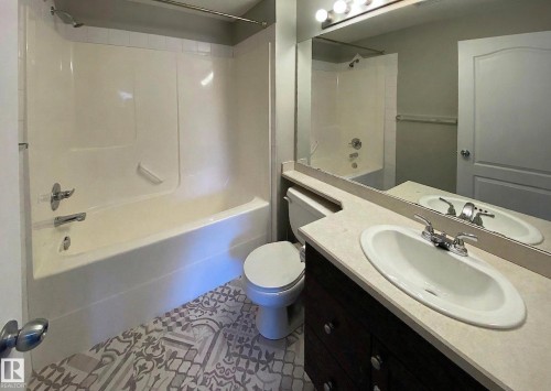 Bathroom featuring a white bathtub and shower combination, a vanity with an oval sink, and patterned floor tiles - #6125 7331 South Terwillegar Dr Nw, Edmonton, AB - Indoor Photo Showing Bathroom