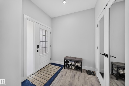 Entryway featuring a white door with frosted glass panels, a full-length mirrored door, wood-finish flooring, and recessed ceiling lighting - 3217 Pelerin Crescent, Beaumont, AB - Indoor