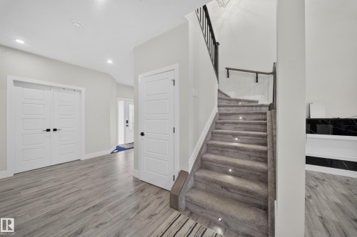 Wood-finish flooring, recessed lighting, white interior doors, and a carpeted staircase with integrated step lighting - 3217 Pelerin Crescent, Beaumont, AB - Indoor Photo Showing Other Room