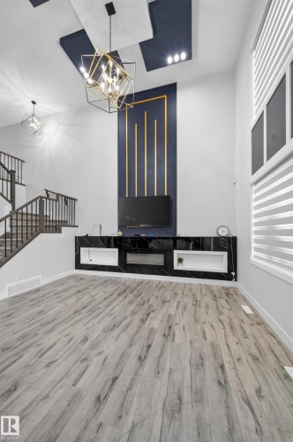 Wood-finish flooring throughout, with a built-in media console featuring a black marble-look finish and integrated electric fireplace - 3217 Pelerin Crescent, Beaumont, AB - Indoor Photo Showing Other Room