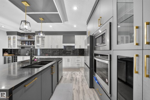 Spacious kitchen with a large island, double basin sink, stainless steel appliances, and wood-finish flooring - 3217 Pelerin Crescent, Beaumont, AB - Indoor Photo Showing Kitchen With Double Sink With Upgraded Kitchen