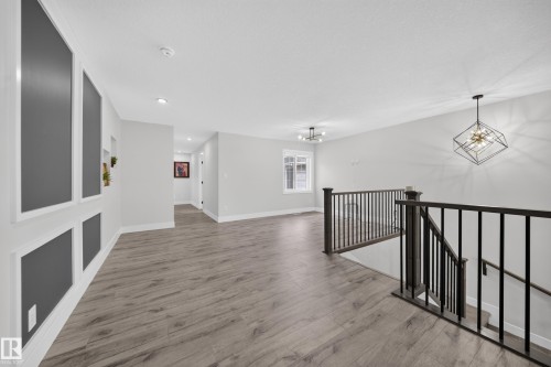 Wood-finish flooring throughout, featuring a staircase with dark wood newel posts and balusters - 3217 Pelerin Crescent, Beaumont, AB - Indoor Photo Showing Other Room