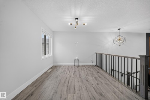 Wood-finish flooring with crisp white walls and trim - 3217 Pelerin Crescent, Beaumont, AB - Indoor Photo Showing Other Room