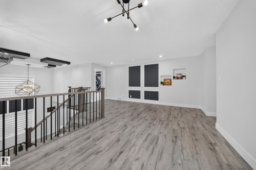 Wood-finish flooring, recessed lighting, built-in wall niches, and a contemporary chandelier - 3217 Pelerin Crescent, Beaumont, AB - Indoor Photo Showing Other Room