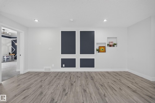 Wood-finish flooring, recessed lighting, built-in wall niches, and a contrasting accent wall with white trim - 3217 Pelerin Crescent, Beaumont, AB - Indoor Photo Showing Other Room