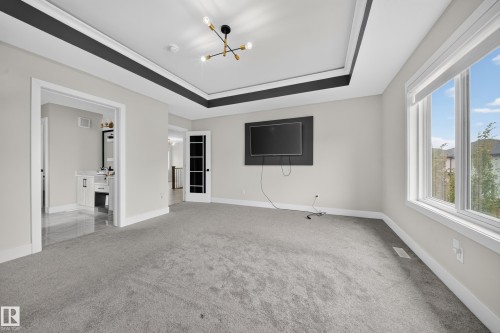 Recessed ceiling with contrasting trim, contemporary light fixture, gray carpeting, and a built-in media wall - 3217 Pelerin Crescent, Beaumont, AB - Indoor