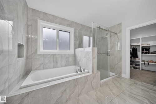 Soaking tub with a wall-mounted niche, glass-enclosed shower, and full-height wall and floor tile - 3217 Pelerin Crescent, Beaumont, AB - Indoor Photo Showing Bathroom